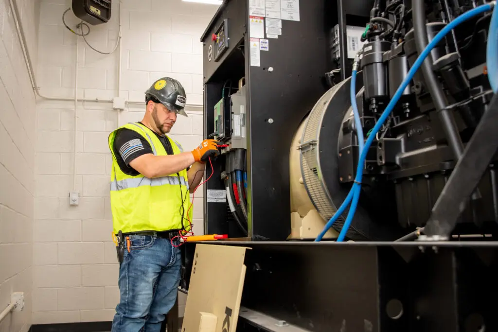 Electrician in hi-vis vest working on large electrical panel box