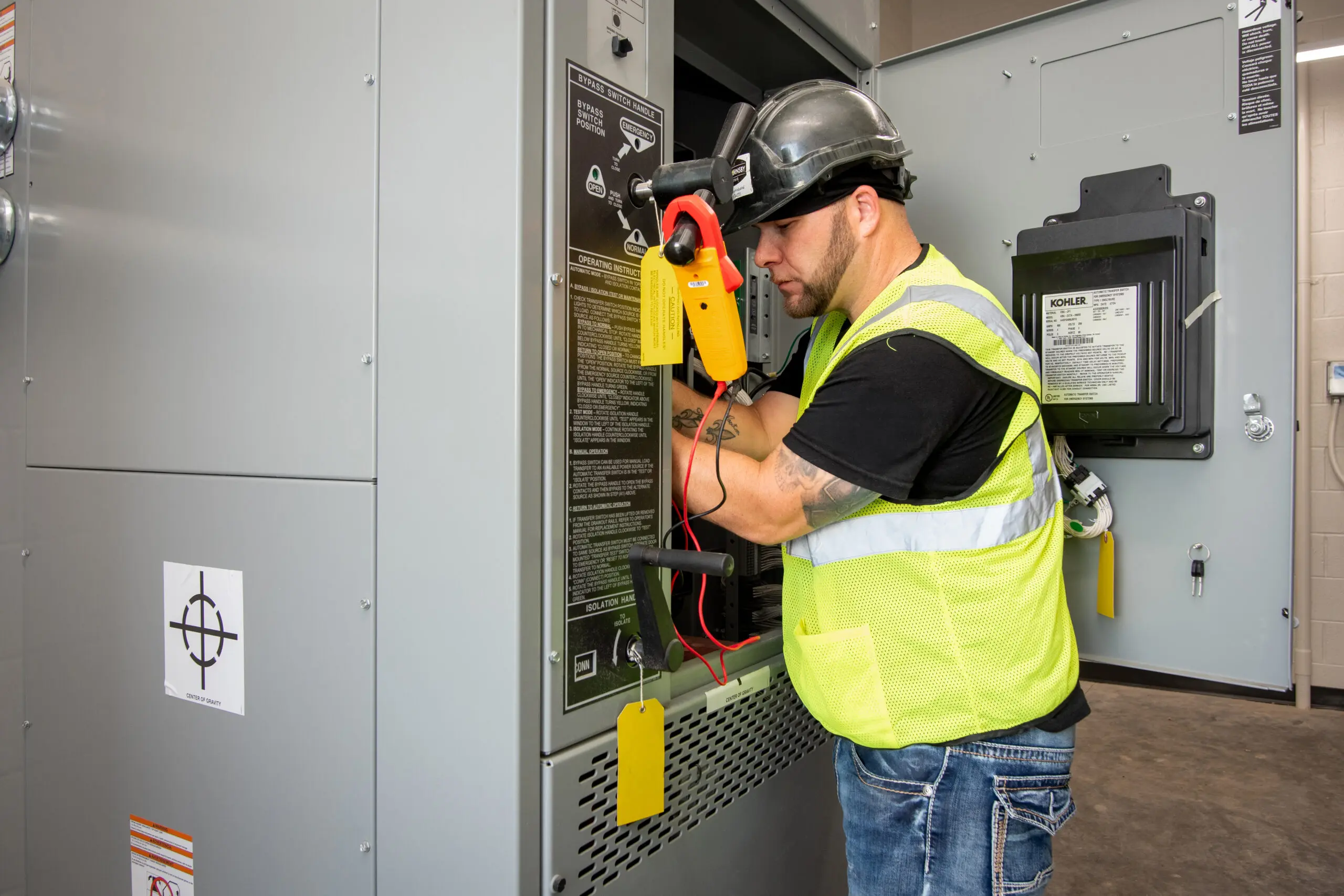 Electrician in hi-vis vest working on large electrical panel